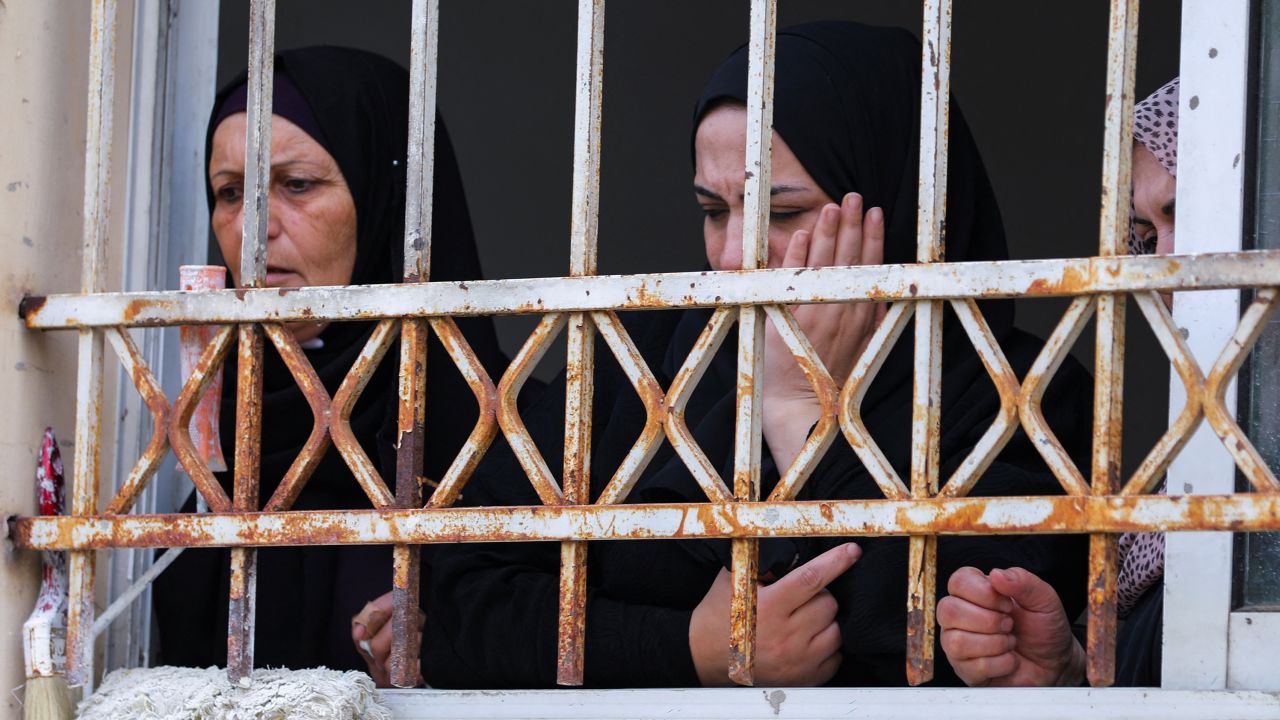 Mourners attend Amjad al-Fayed's funeral from a window in Jenin.
