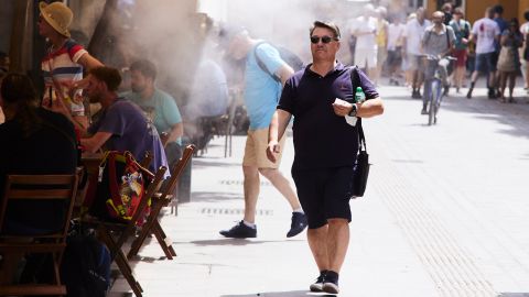 A man passes under sprinklers installed in a bar on May 19, the first day of high temperatures, in Seville, Spain.