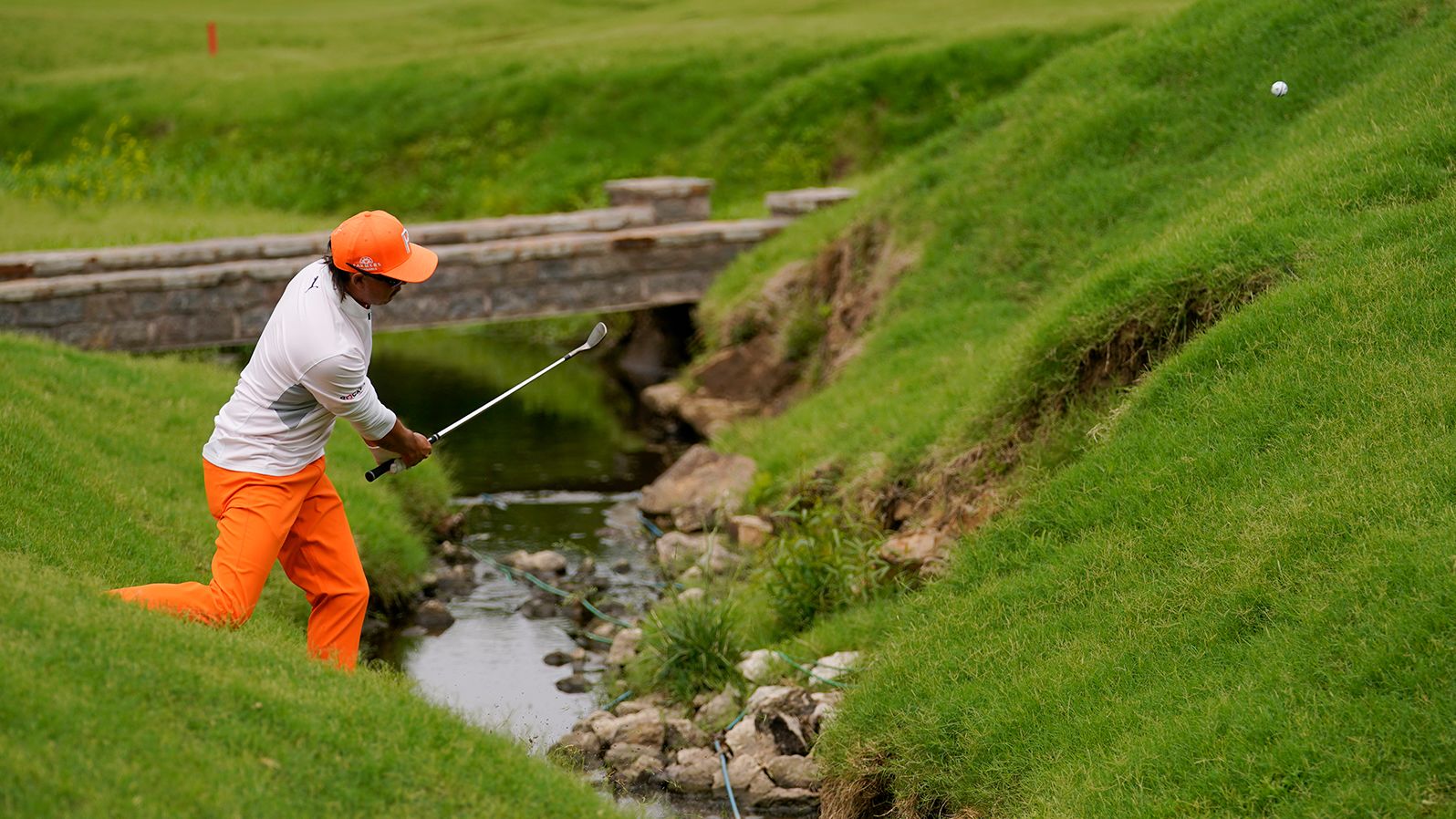 Rickie Fowler hits from the hazard on the 17th hole.
