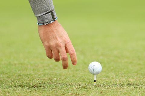 Rory McIlroy places his golf ball on the fourth tee wearing a bracelet with his daughter's name on it.