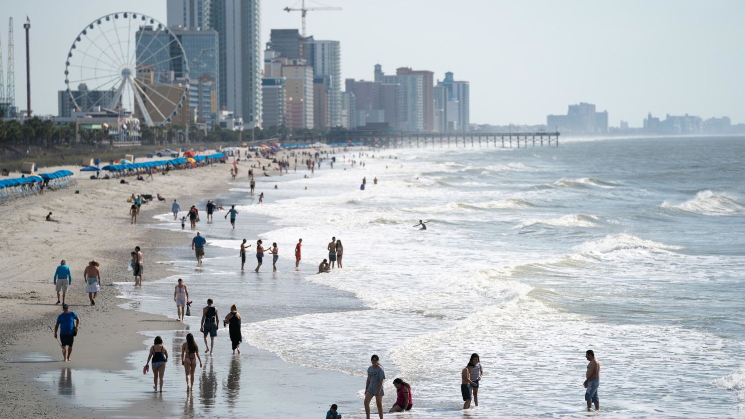 MYRTLE BEACH, SC - MAY 29: People walk along the beach the morning of May 29, 2021 in Myrtle Beach, South Carolina. Myrtle Beach is the No. 3 top destination for road trips on Memorial Day, according to AAA Carolinas. (Photo by Sean Rayford/Getty Images)