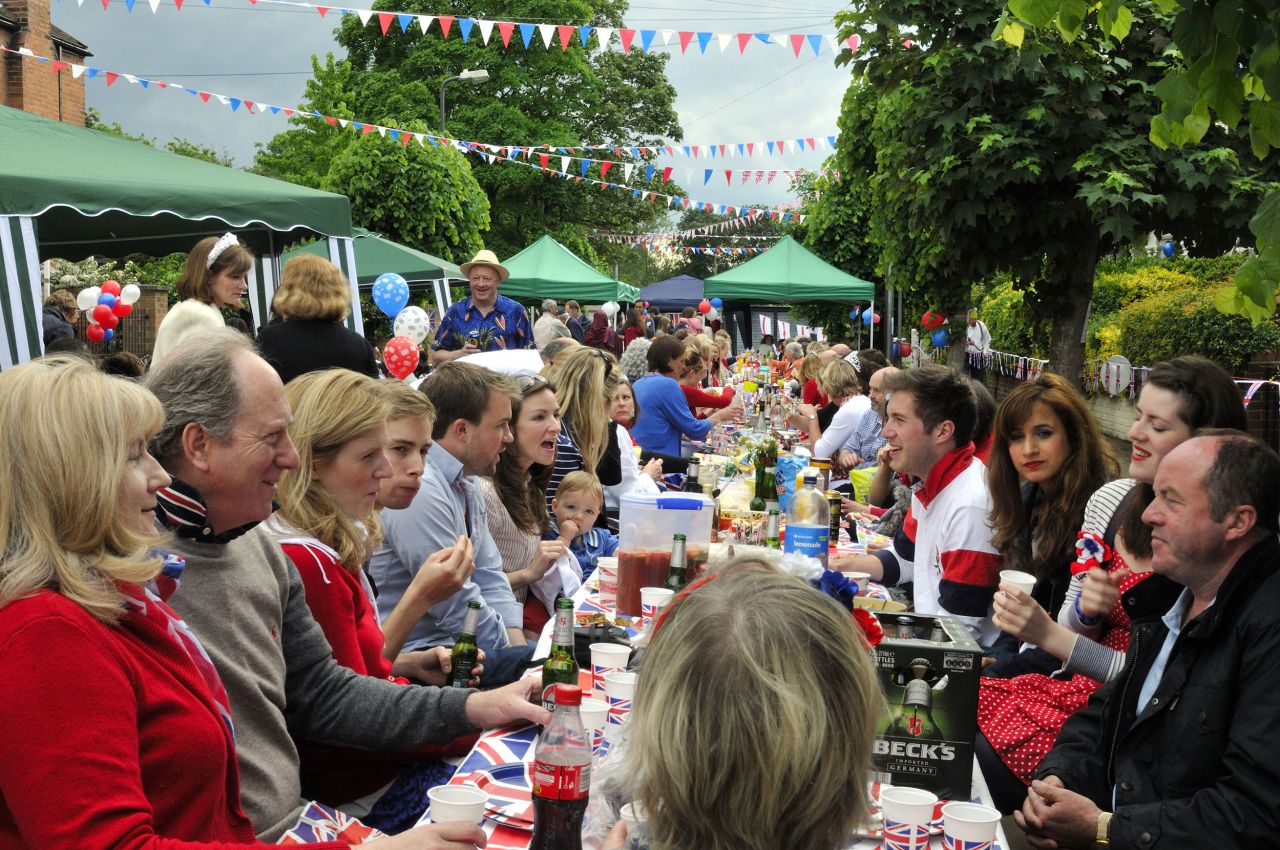 Residents of Melbourne Road, Wimbledon, in southwest London sit at a long Union Jack-bedecked table, enjoying food, drink and conversation during their 2002 Golden Jubilee street party.