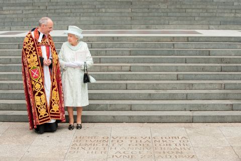 Accompanied by the Dean of St. Paul's, David Ison, the Queen views an inscription at the foot of the steps of the cathedral commemorating Queen Victoria's 60th anniversary on the throne.