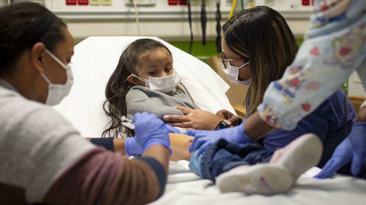 Trial participant Elena Rosales (center), 3, receives the Moderna Covid-19 vaccine from nurse Lela Lartey (left) with her mother, Mariaelena Lozano (right), by her side, on December 7, 2021, at Lurie Children's Hospital of Chicago.