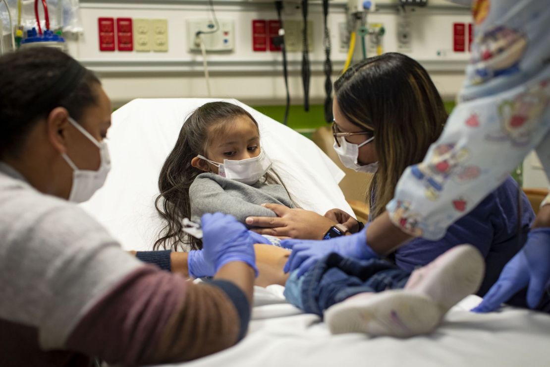 Trial participant Elena Rosales (center), 3, receives the Moderna Covid-19 vaccine from nurse Lela Lartey (left) with her mother, Mariaelena Lozano (right), by her side, on December 7, 2021, at Lurie Children's Hospital of Chicago.