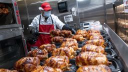A worker wearing a protective mask removes rotisserie chicken from skewers inside a Costco store in San Francisco, California, U.S., on Wednesday, March 3, 2021. 
