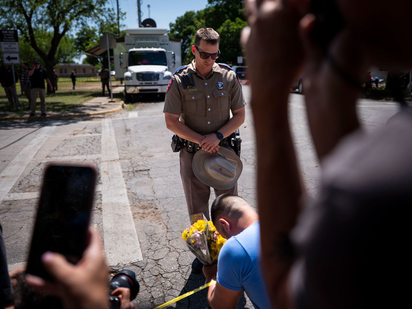 An officer with the Texas Highway Patrol prays with a community member before taking his flowers to the growing memorial in front of Robb Elementary School.