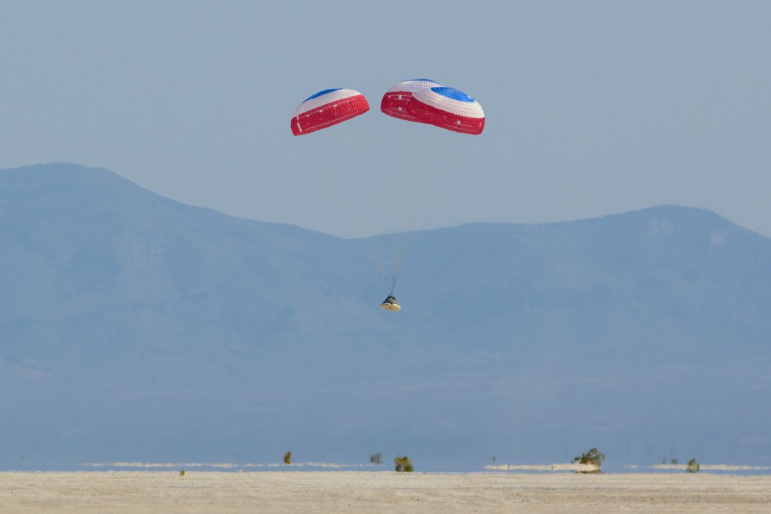 A Boeing Starliner capsule is lowered to Earth underneath three parachutes as it landed in the New Mexico desert. Photo Credit: (NASA/Bill Ingalls)