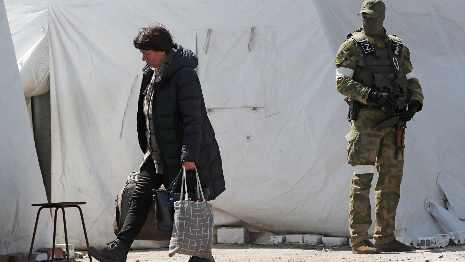 A woman carries bags as evacuees, including civilians who left the area near Azovstal steel plant in Mariupol, arrive at a temporary accommodation center in the village of Bezimenne in the Donetsk Region, Ukraine May 1, 2022. 