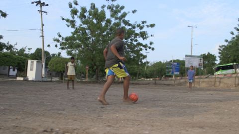 Barefoot kids play football on the sandy pitch in front of Diaz's family home in Barrancas earlier this month.