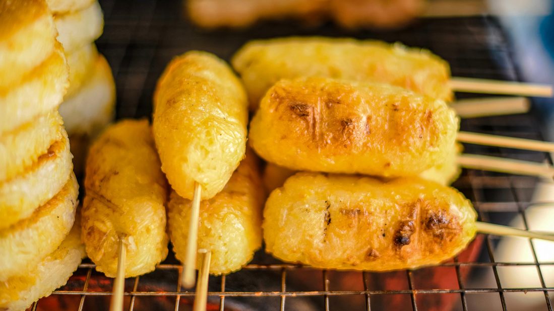 <strong>Khao jee, Laos:</strong> A grilled sticky rice patty on a stick with a thin egg coating and a light char from the grill, khao jee has a radiant golden hue, a sweet and nutty flavor and a delightfully chewy texture.