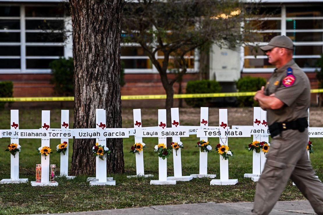 Police officers walk past a makeshift memorial for the shooting victims at Robb Elementary School in Uvalde, Texas, on Thursday.