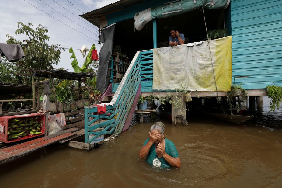 Iracema Guimaraes da Costa wades through floodwaters in front of her relatives' house in Careiro da Várzea, Brazil, on Friday, May 20. Several riverside villages were affected by flooding.  