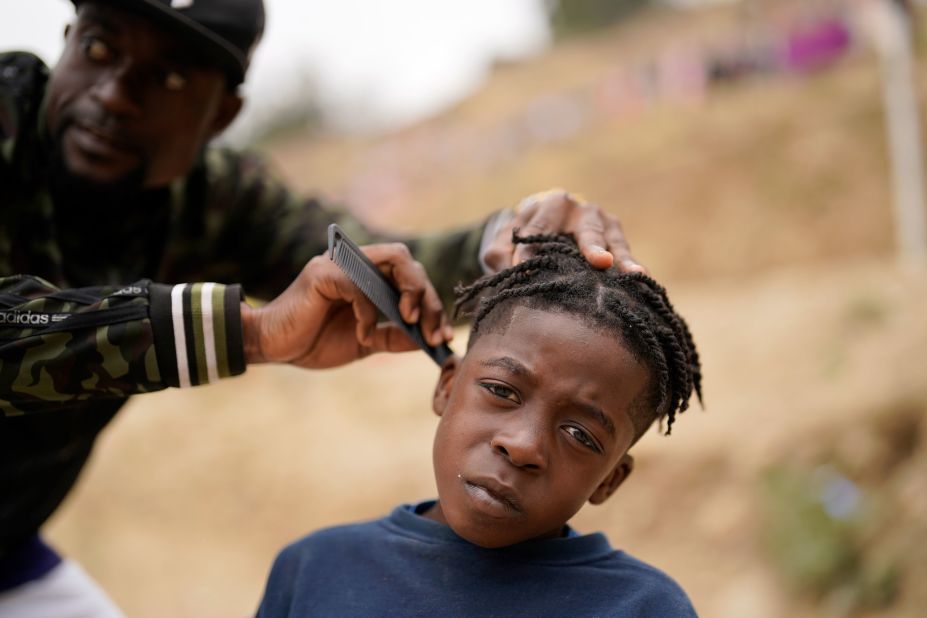Wiggins Nordelus cuts his son Samuel's hair outside of a migrant shelter in Tijuana, Mexico, on Monday, May 23. Nordelus, who is from Haiti, has been waiting in Mexico as he hopes to apply for asylum in the United States. 