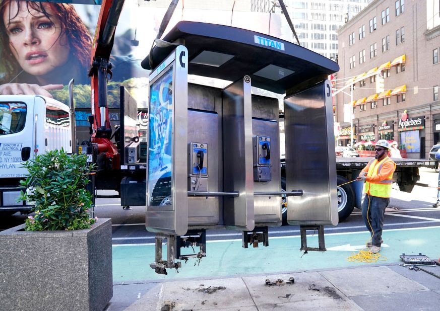 Workers remove New York City's last pay phone on Monday, May 23. It was in midtown Manhattan near Seventh Avenue and 50th Street.