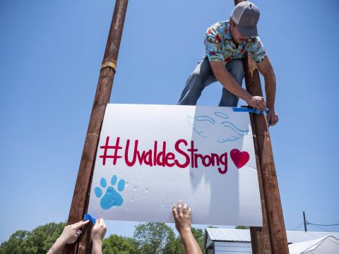 Tyler Garcia raises up a sign that says "#UvaldeStrong" during a car wash and food sale Thursday that was raising money for the families of those who lost loved ones in the shooting. 