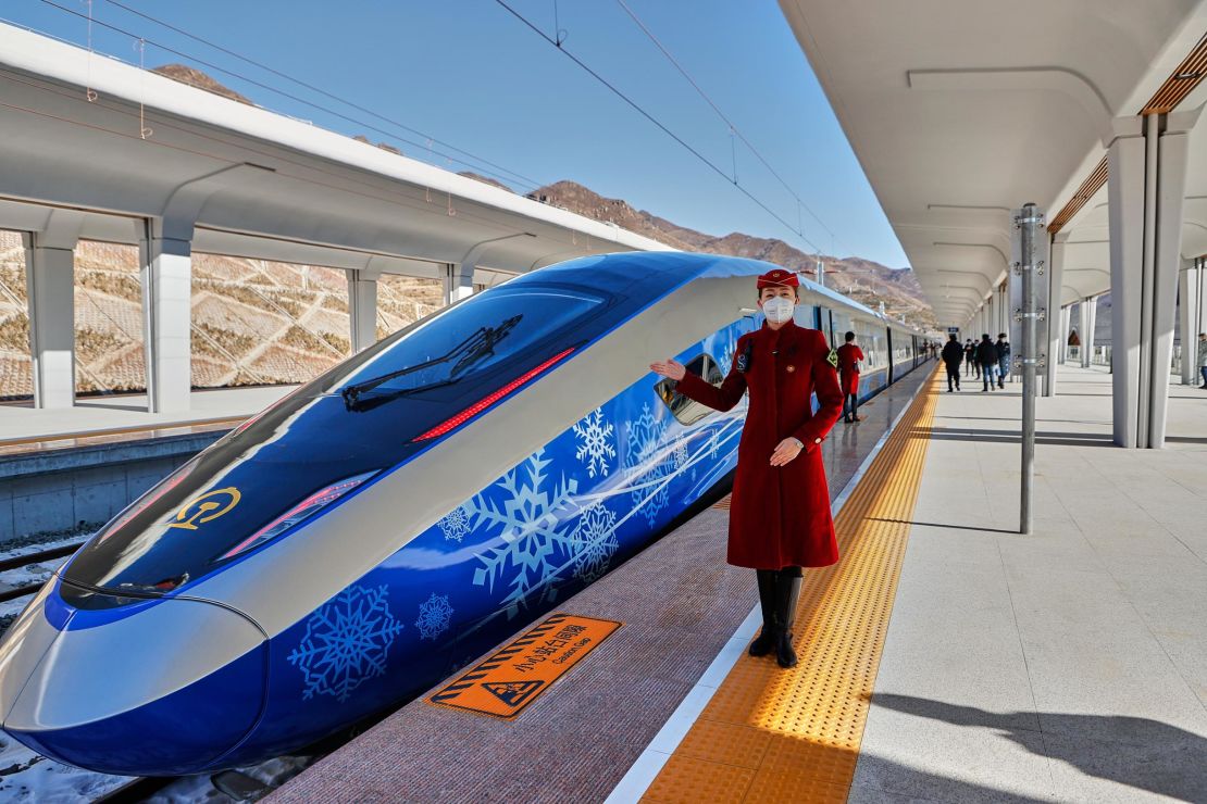 A train attendant poses beside an "intelligent" Fuxing bullet train on January 6, 2022 in China. 