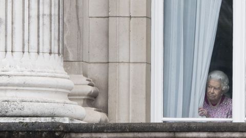 The monarch peers through the curtains of Buckingham Palace as she waits for the Patrons Lunch to start on the Mall in central London on June 12, 2016. 