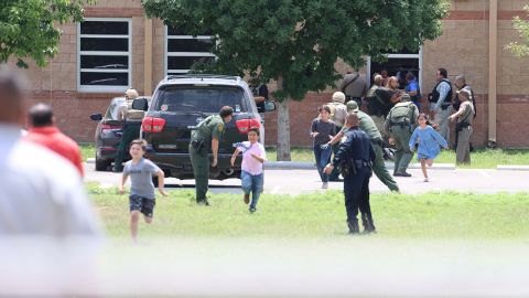 Students run to safety after law enforcement officers helped them escape from a window at the school on Tuesday.