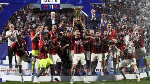 Alessio Romagnoli (center) of AC Milan lifts the Scudetto trophy as his teammates celebrate during the Serie A award ceremony.