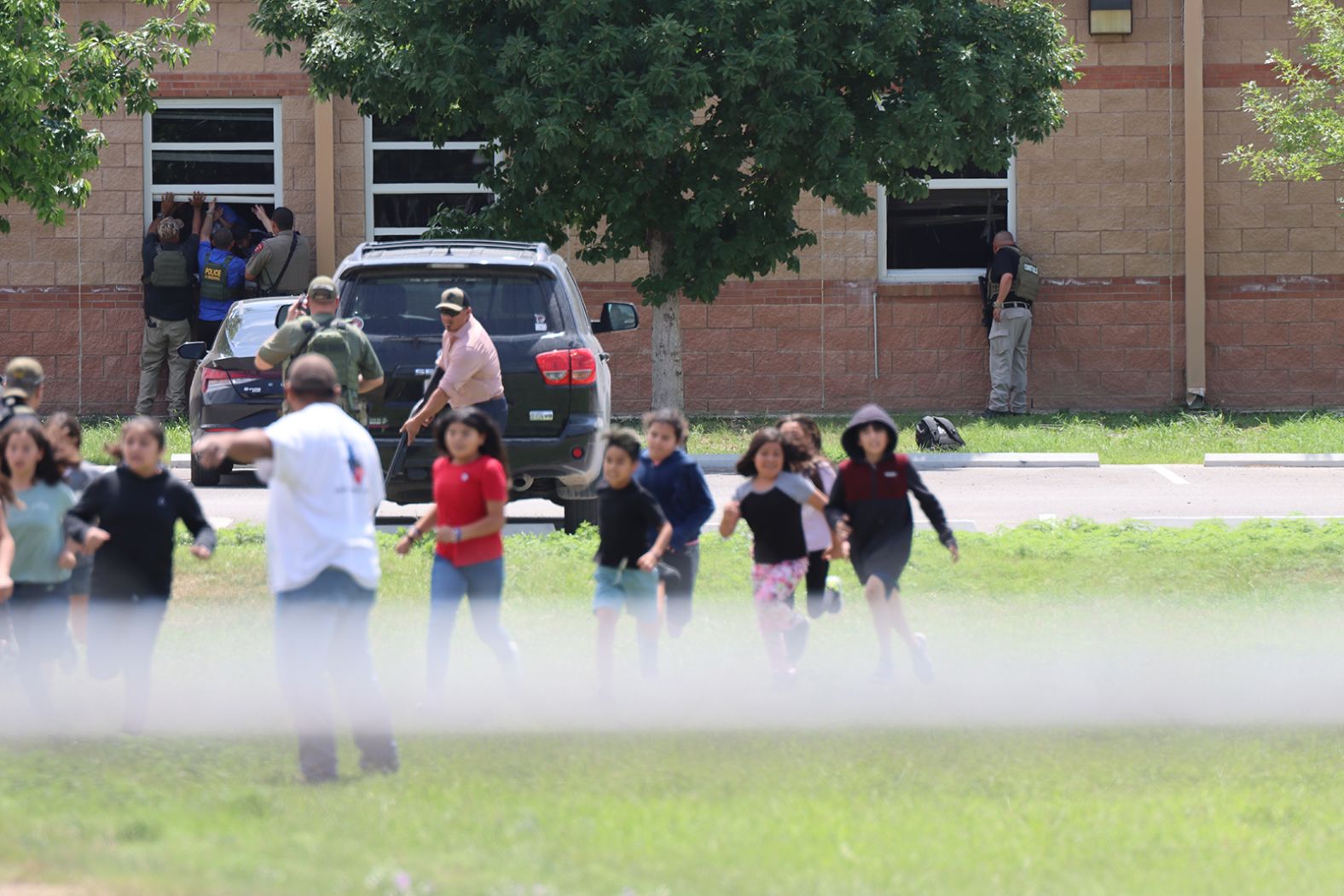 Children run to safety after escaping through a window.