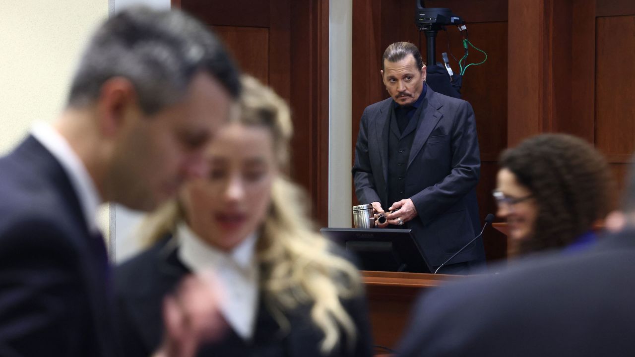 Actress Amber Heard, second from left, speaks to her legal team as actor Johhny Depp stands at the Fairfax County Circuit Court on April 21, 2022.