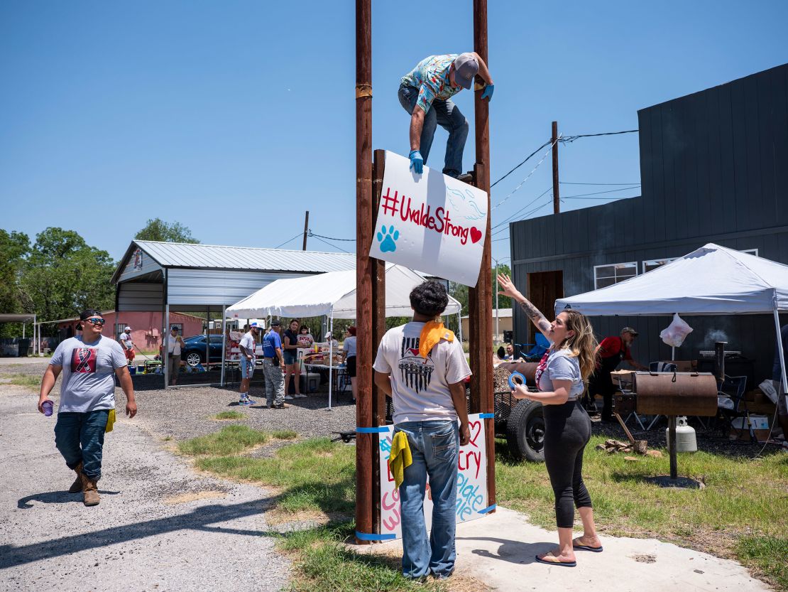 Tyler Garcia, 21, top, raises up a sign during a car wash and food sale to raise money for the families of those killed.