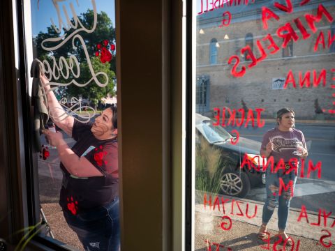Vanessa Palacios, left, and Melissa García write the victims' names on their storefront, Cut Loose Hair Emporium, on Friday, May 27.