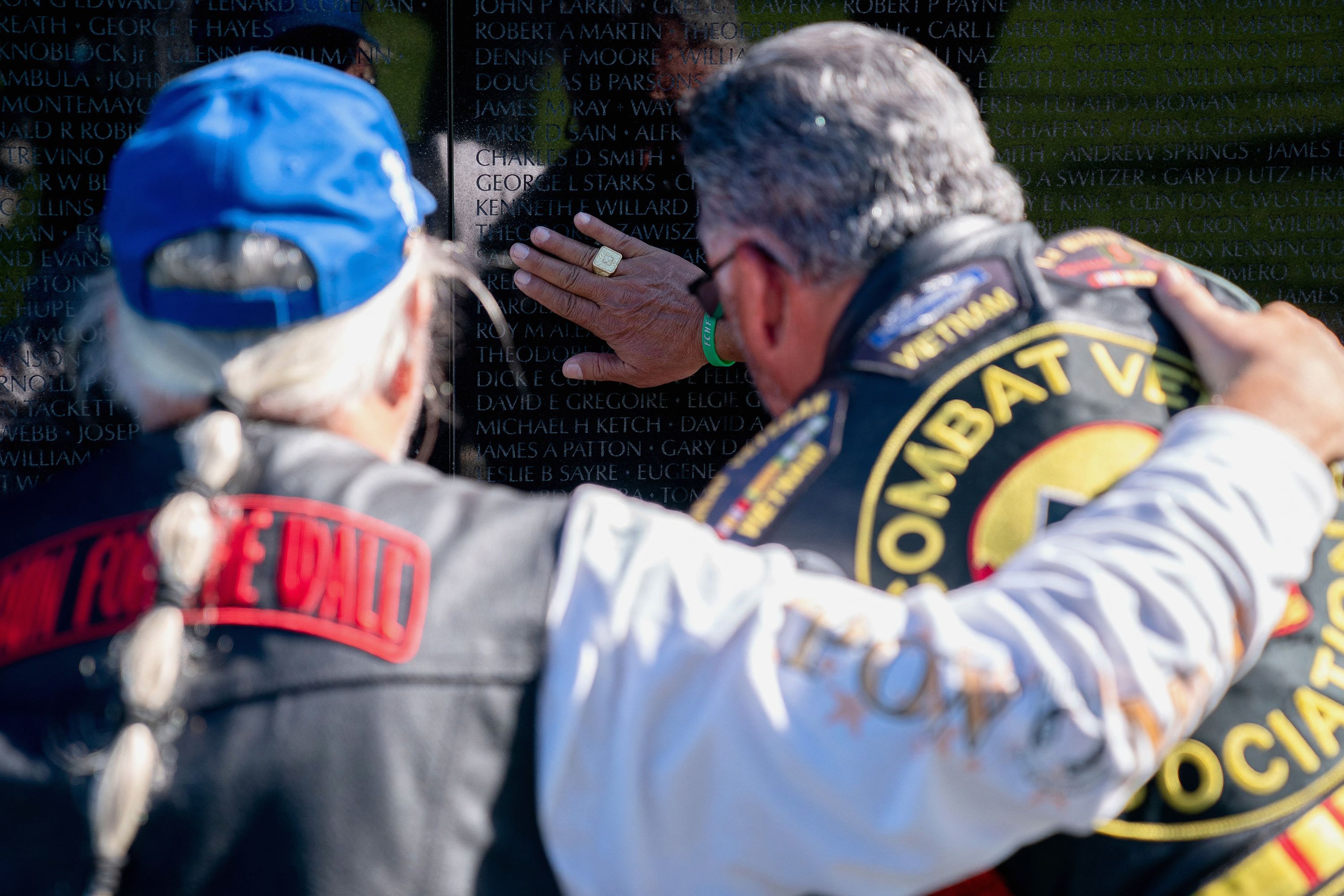 Participants in the Rolling to Remember event touch a veteran's name at the Vietnam Veterans Memorial in Washington, DC.