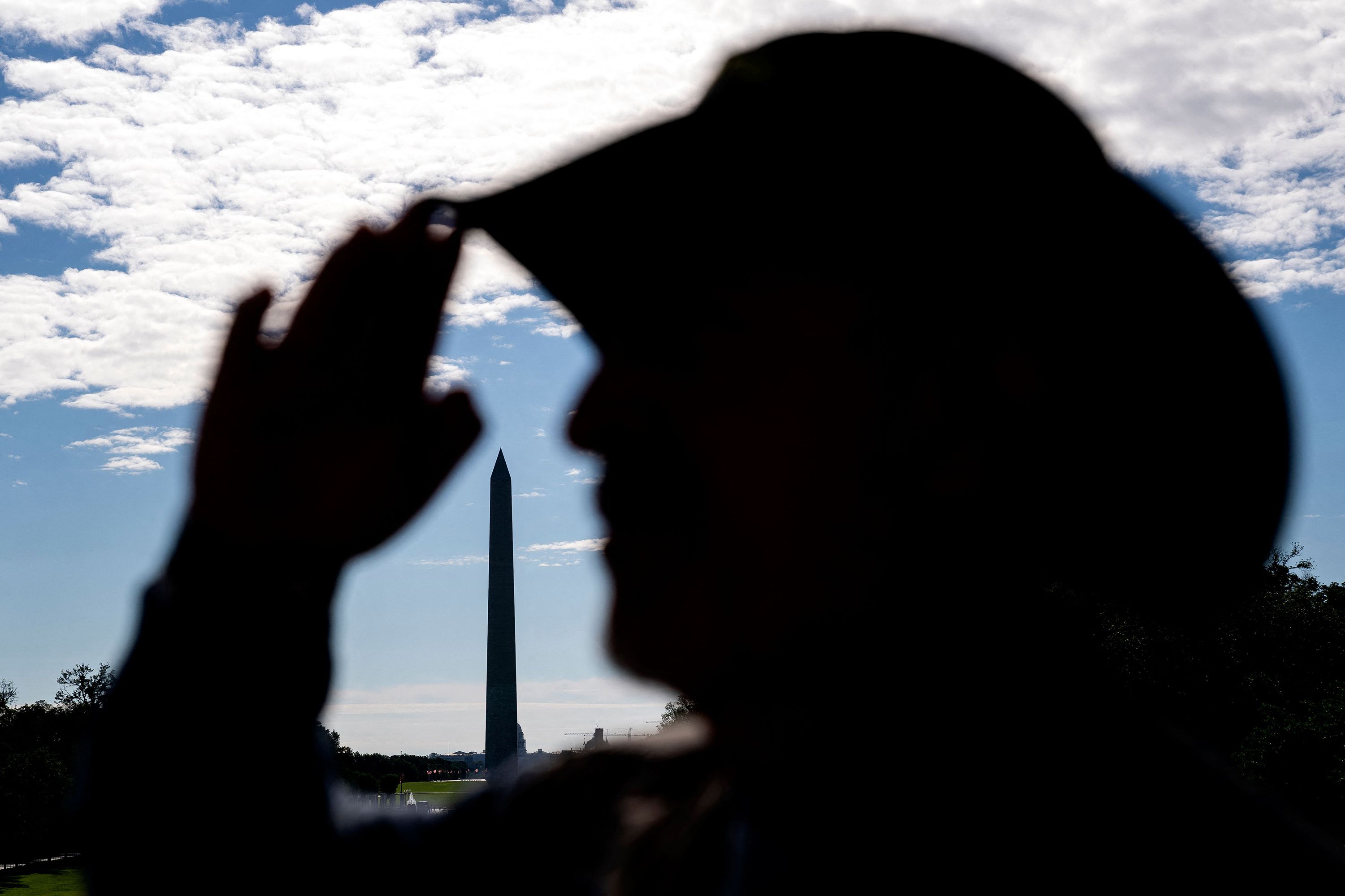 The Washington Monument is seen behind a person saluting during a Memorial Day event on Saturday.