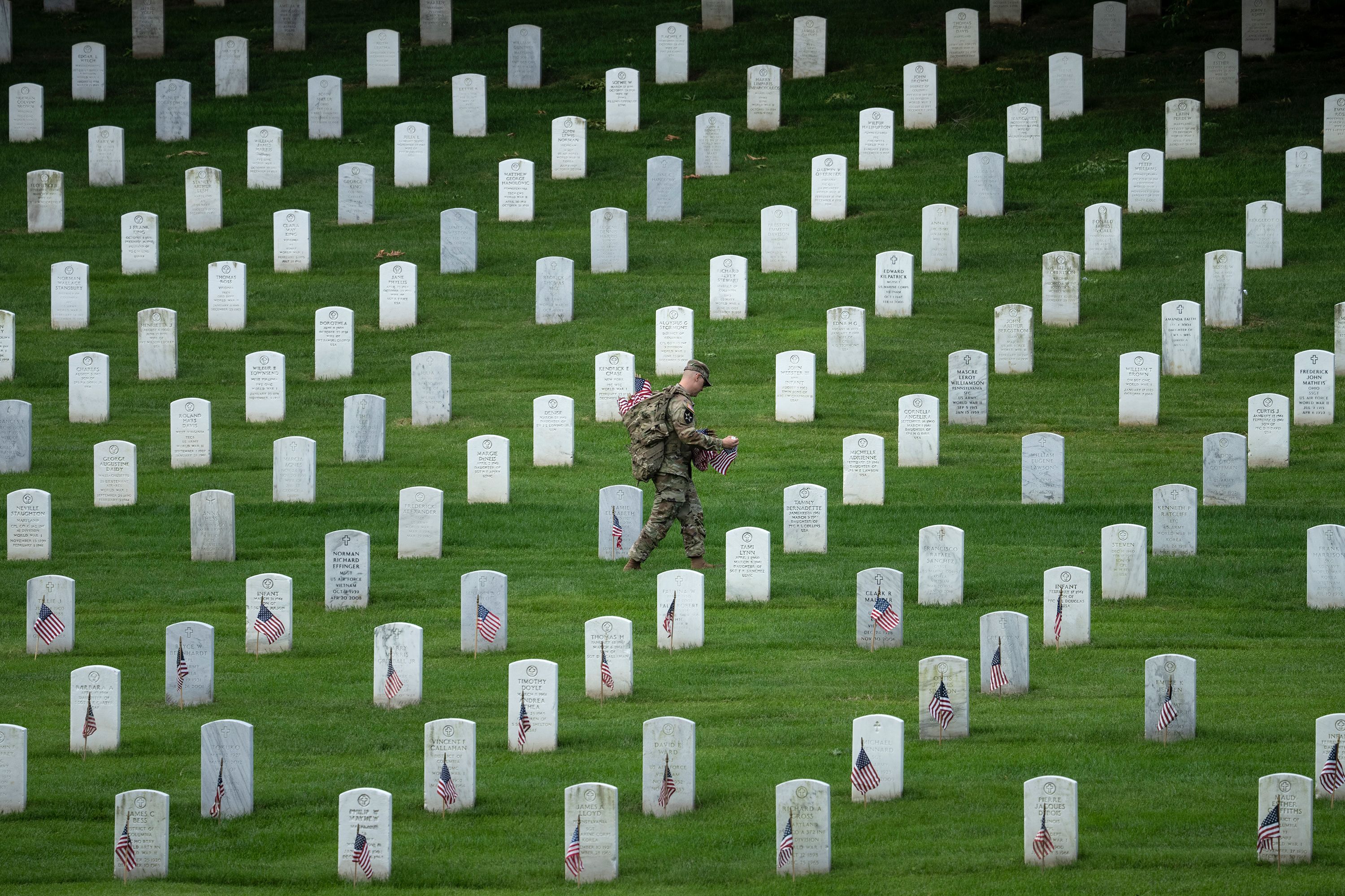 A member of the US Army's 3rd US Infantry Regiment places flags at Arlington National Cemetery on Thursday, May 26.