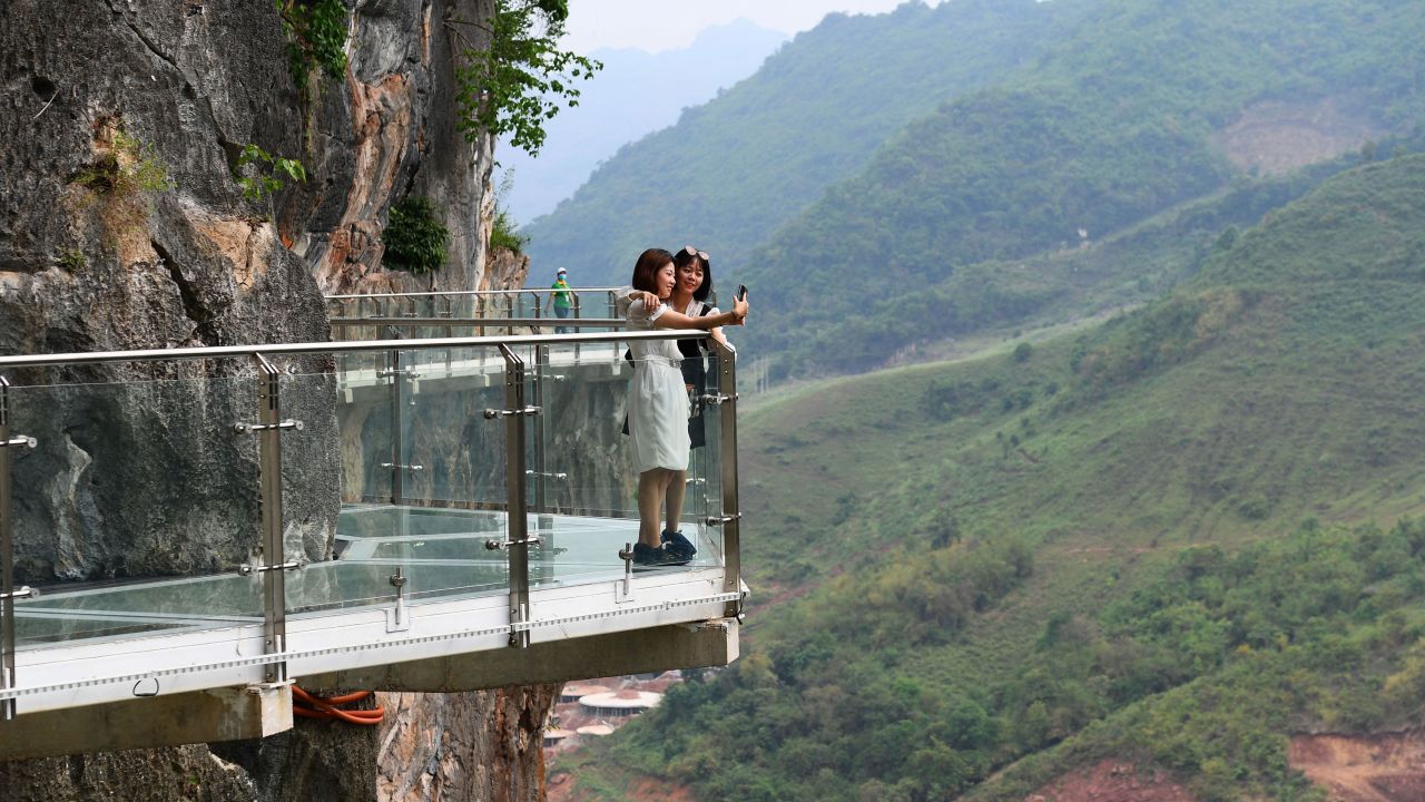 Visitors take photos on the walkway section of the Bach Long glass bridge in Moc Chau district in Vietnam's Son La province on April 29, 2022. (Photo by NHAC NGUYEN/AFP via Getty Images)
