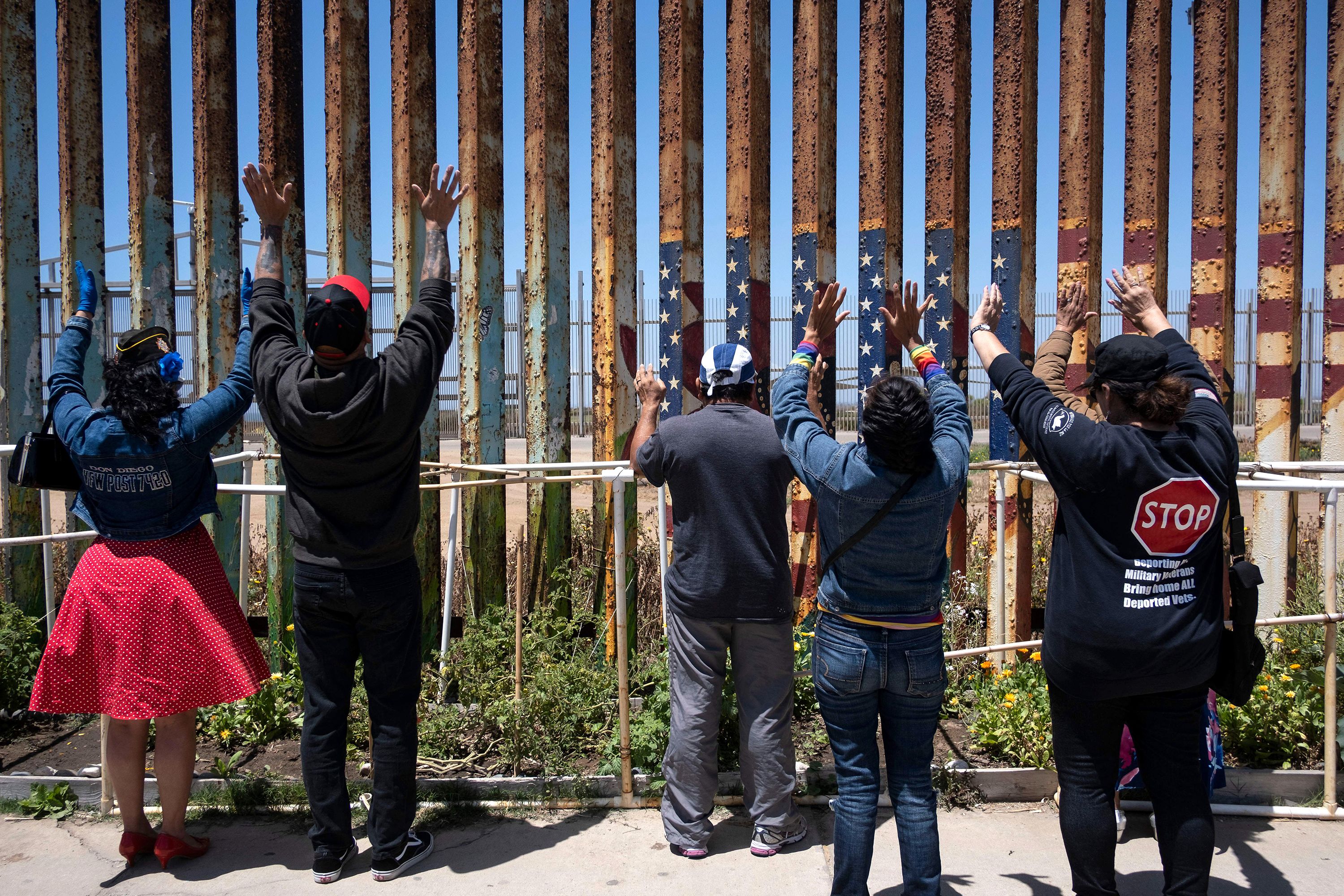 US veterans and their relatives pray during the Remembering our Fallen Exile Deported Veterans event at the US-Mexico border in Playas de Tijuana, Mexico, on Sunday, May 29.