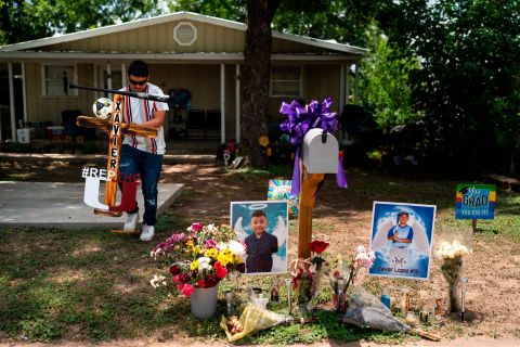 Jose Mata, Xavier Lopez's brother, carries a wooden cross decorated with a baseball bat to place it at a memorial honoring Xavier outside his home in Uvalde on May 31. 