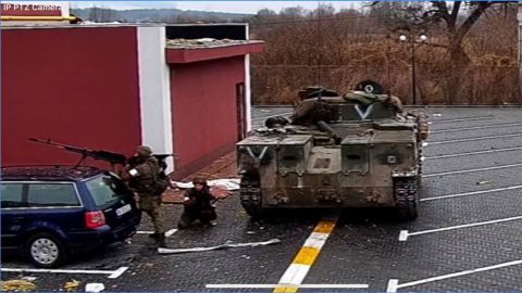 Russian soldiers in the courtyard of the Pokrovsky residential complex in an image taken from the security camera on Thursday, March 3, 2022. A letter V is visible on the armored vehicle.