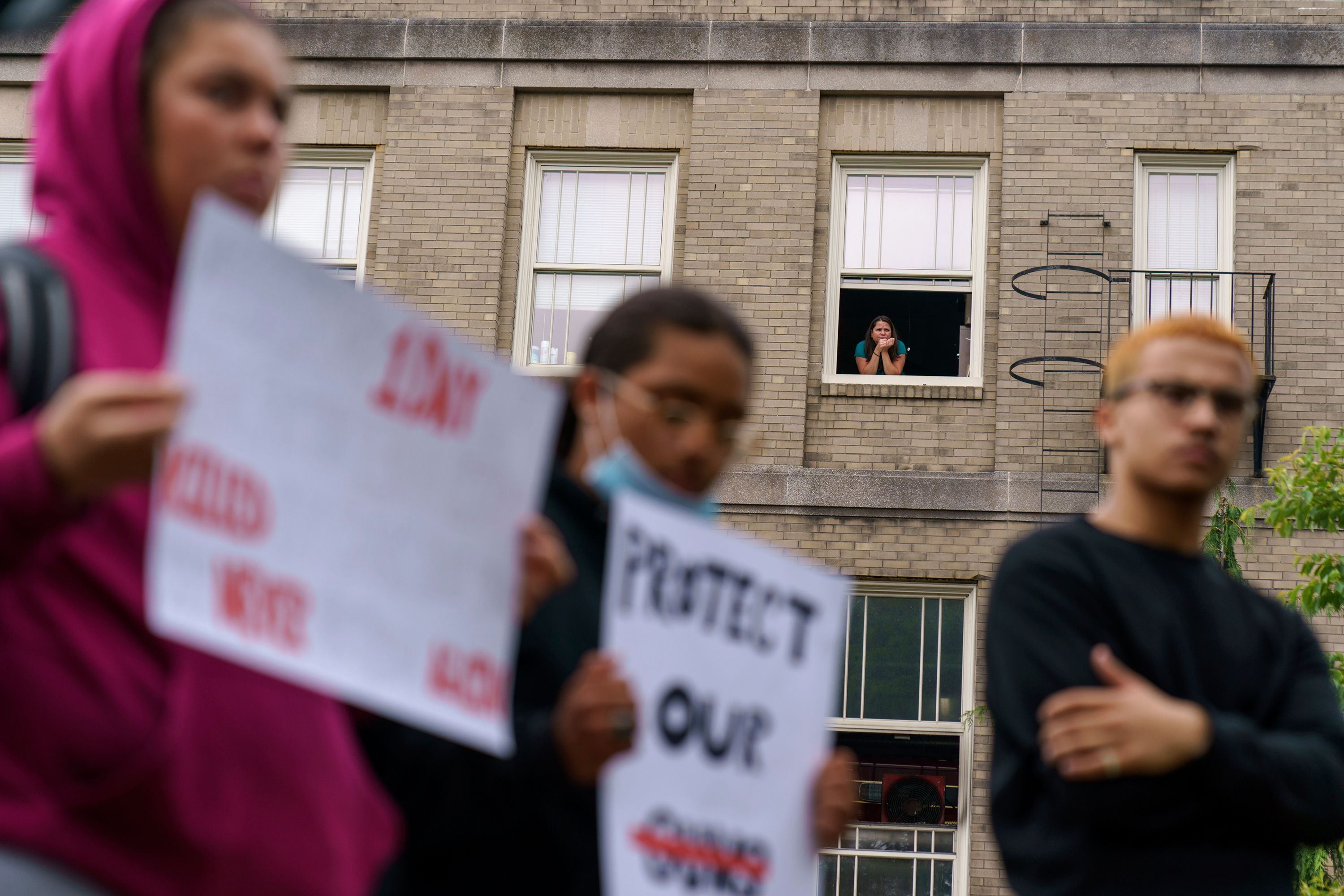 A person looks out of a window in Pawtucket, Rhode Island, as high school students protest the nation's gun policies on Wednesday, June 1.