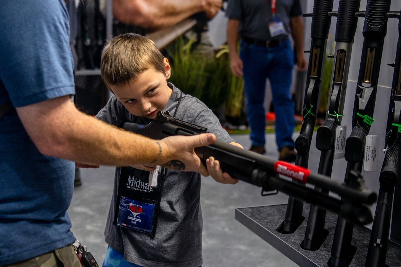 Chris Shelton helps his 7-year-old son, Luke, steady a firearm during the National Rifle Association convention in Houston on Saturday, May 28. He said he has been teaching his son firearm safety over the last three years. 