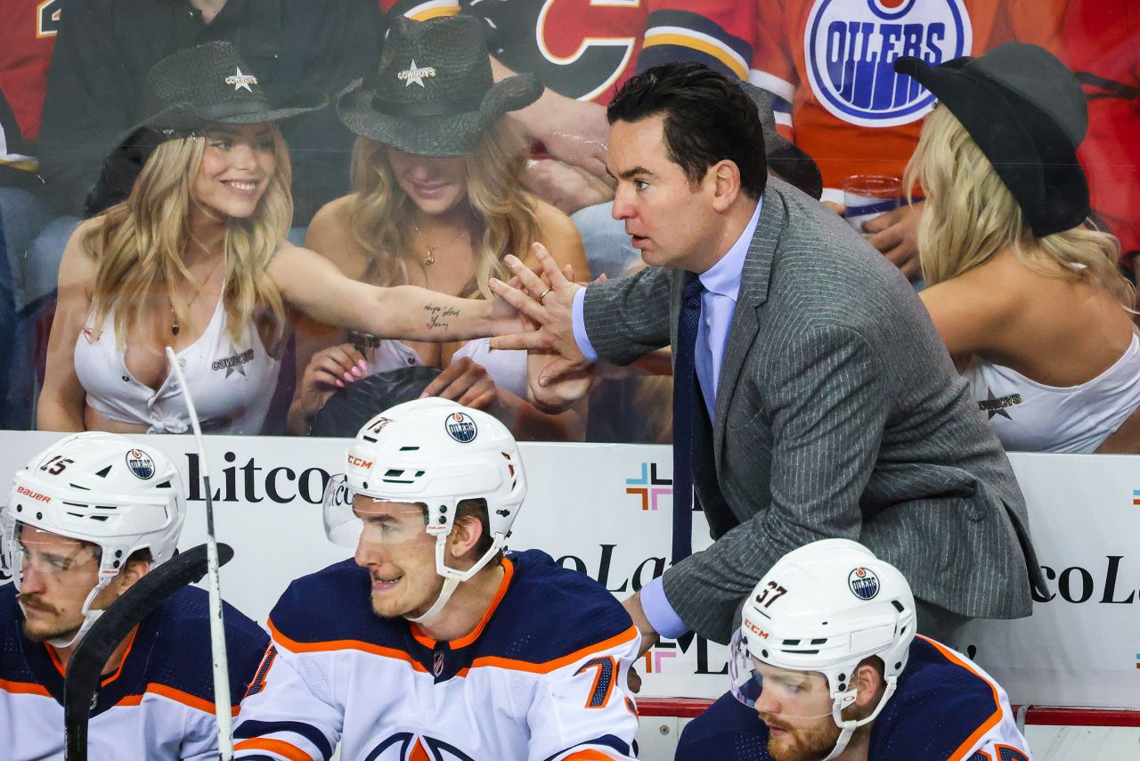 Hockey fans sitting behind Edmonton's bench put their hands on the glass as Oilers head coach Jay Woodcroft watches a Stanley Cup playoff game in Calgary, Alberta, on Thursday, May 26.