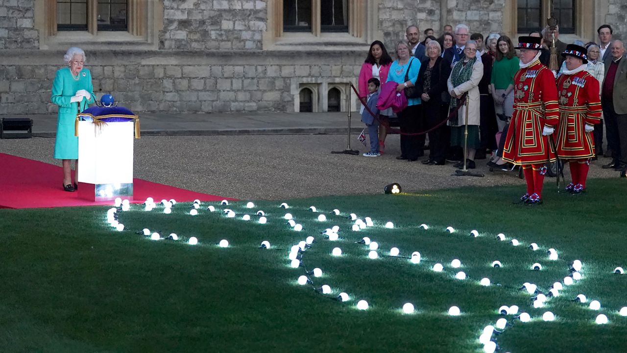 The Queen prepares to touch the Commonwealth of Nations Globe to start the lighting of the Principal Beacon outside Buckingham Palace on Thursday. 