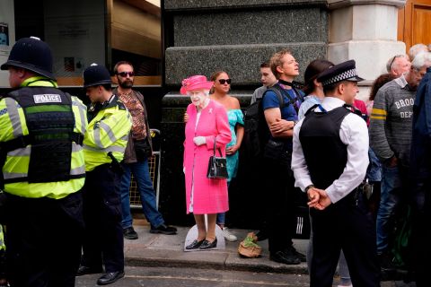 A woman holds a cutout picture of the Queen while waiting outside St Paul's Cathedral on Friday.