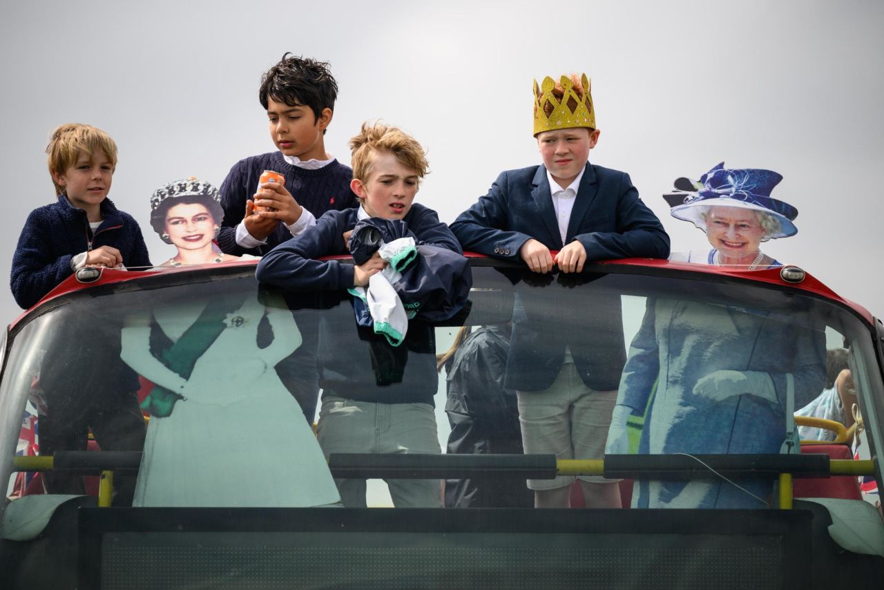Boys ride a bus in Epsom alongside cardboard cutouts of the Queen.
