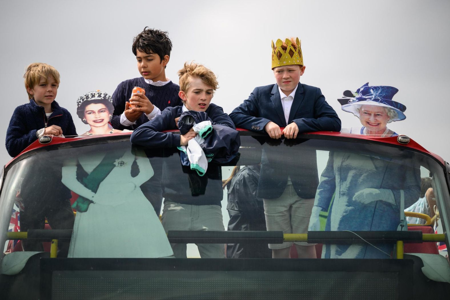 Boys ride a bus in Epsom alongside cardboard cutouts of the Queen.