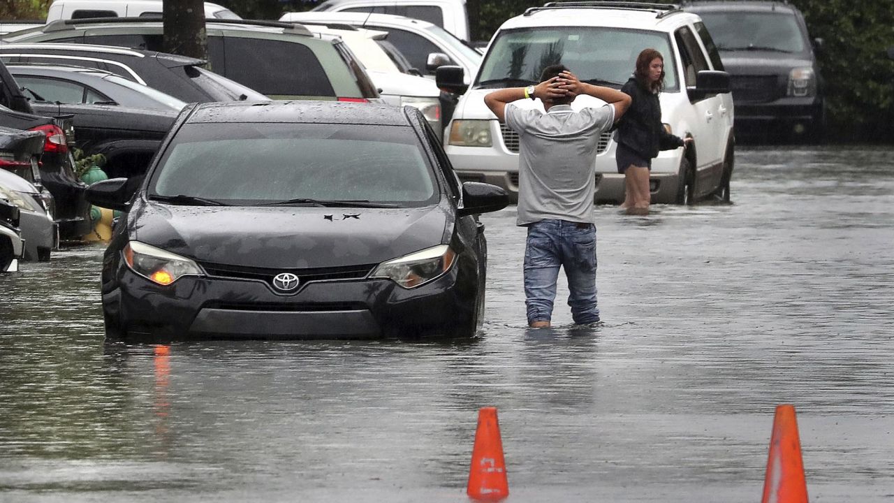 A driver climbs out of his stalled car after he tried to move it to higher ground in a parking lot in Dania Beach, Florida, Saturday.