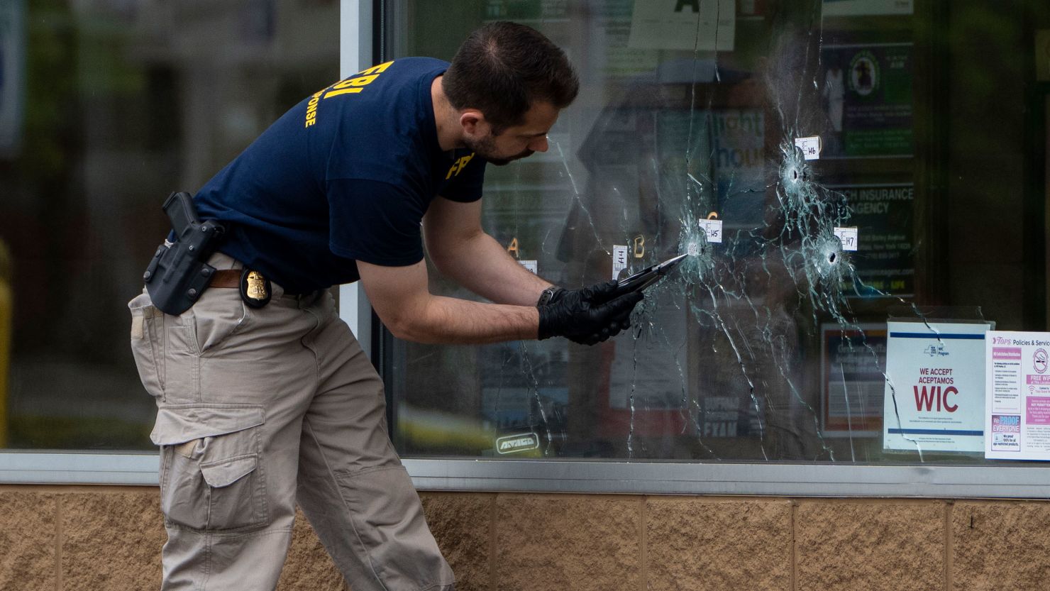 Bullet holes are seen in the window of Tops Friendly Market in Buffalo, New York, on Monday, May 16, 2022, as federal investigators work the scene of a mass shooting. 