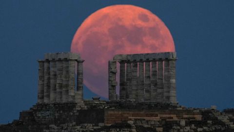 A full strawberry moon rises behind the Temple of Poseidon at Cape Sounion, Greece, in June 2021.