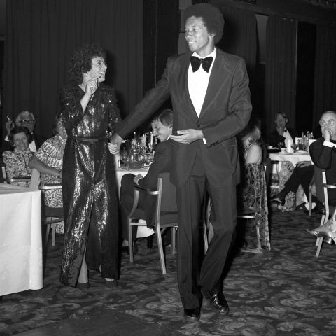 Ashe leads fellow Wimbledon champion Billie Jean King onto the dance floor at a post-tournament ball in 1975.
