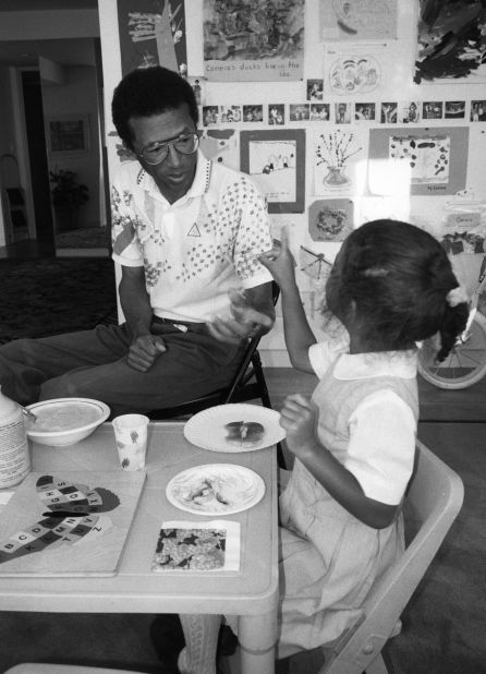 Ashe sits with his daughter, Camera, in 1990. He and his wife adopted Camera in 1986.
