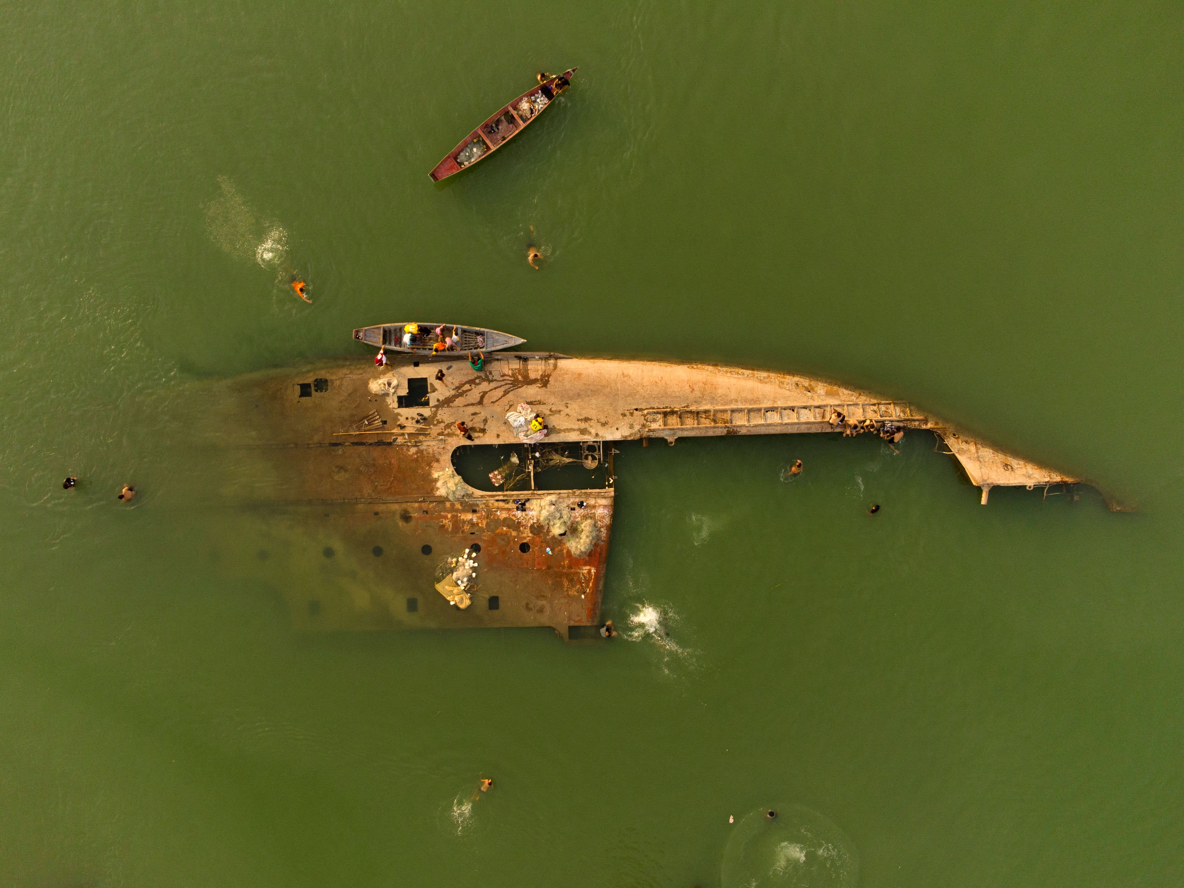 People swim in the Shatt al-Arab waterway near a shipwreck in Basra, Iraq, on Monday, June 6.