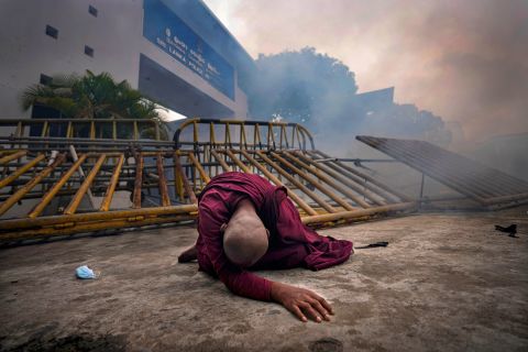 A Buddhist nun falls next to a barricade after inhaling tear gas during a protest outside police headquarters in Colombo, Sri Lanka, on Thursday, June 9. The country's <a href=
