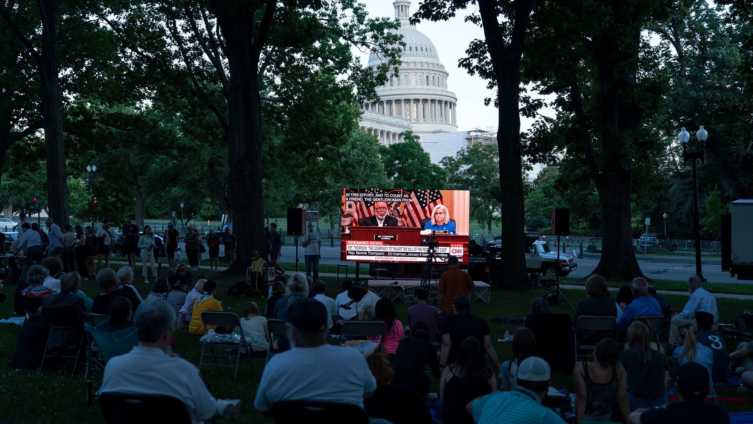 People gather in a park outside the Capitol to watch the hearing on June 9.